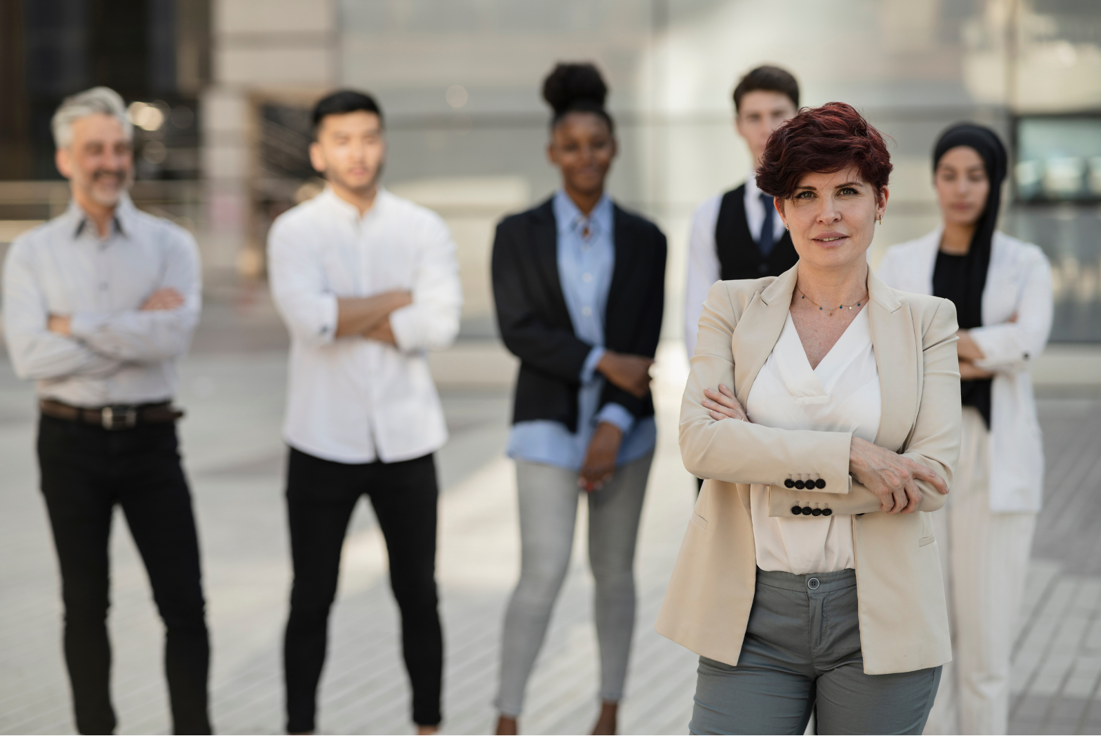 A diverse group of professionals standing in a row, with Nikki Gianni, a leadership architect, confident in the foreground.