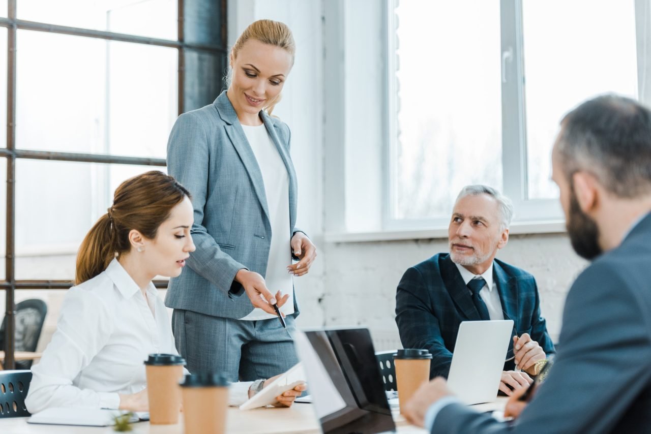 A group of business people gathered around a table in an office for a leadership coaching session.