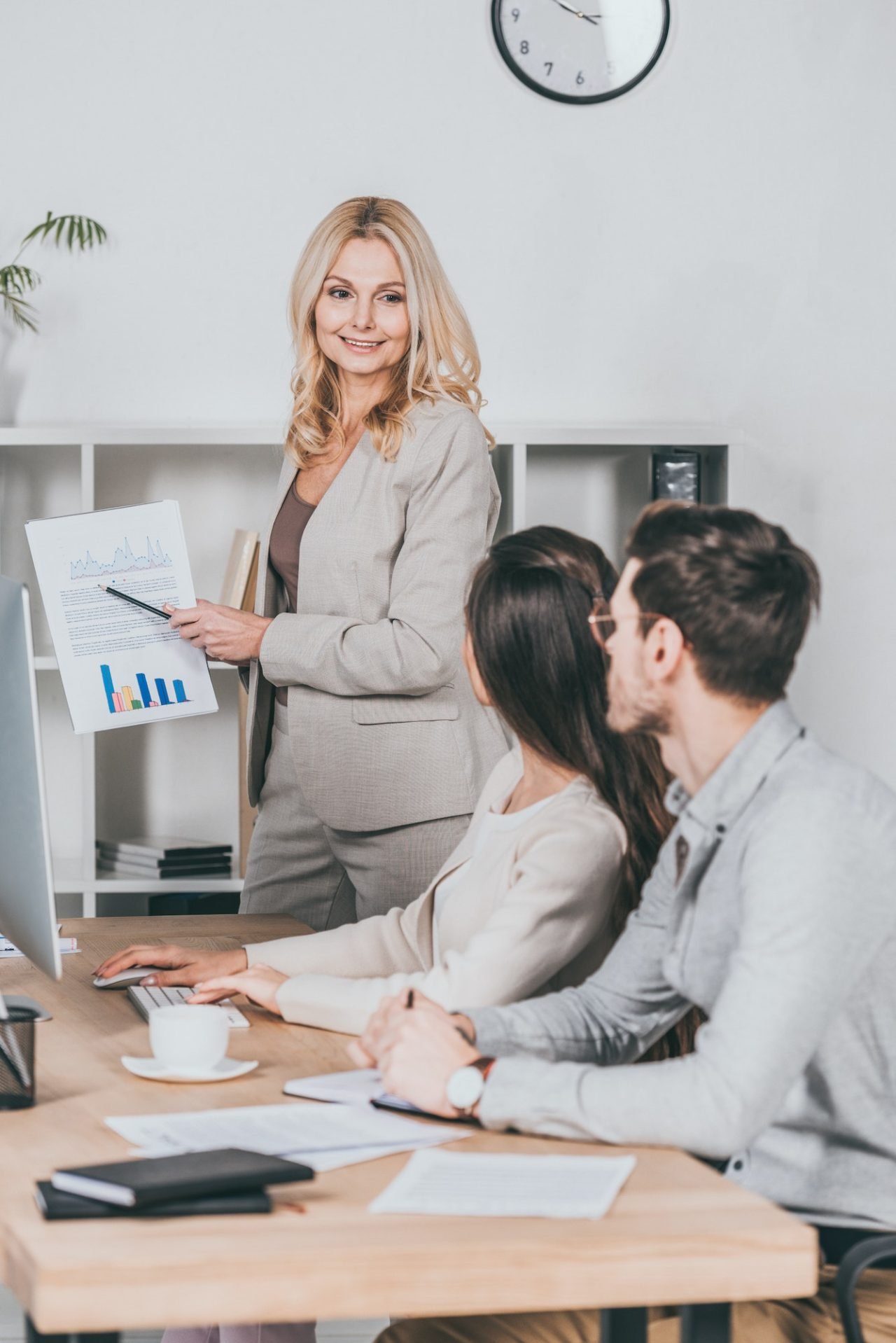 A business woman is giving a presentation on leadership to a group of people in an office.