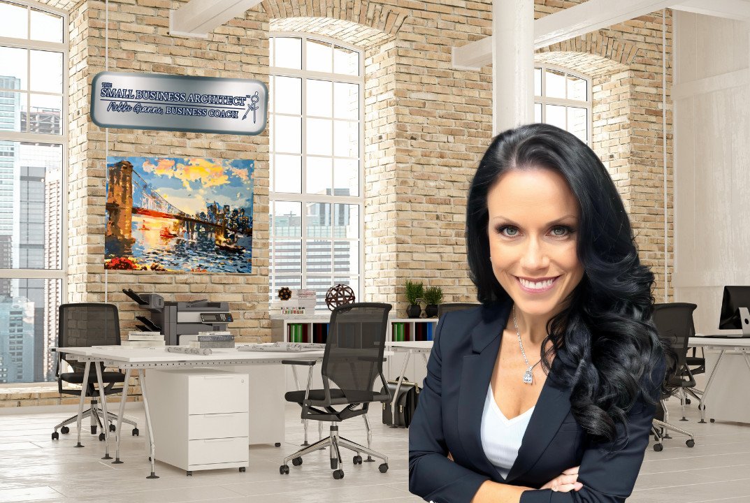 Confident businesswoman standing in a modern office with exposed brick walls, a large window, and several desks.